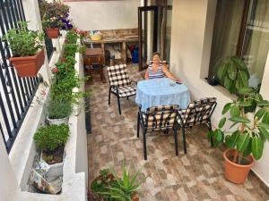 Eine Frau, die auf einem Balkon am Tisch sitzt. in der Unterkunft Sarafovo Sea & Forest in Burgas City