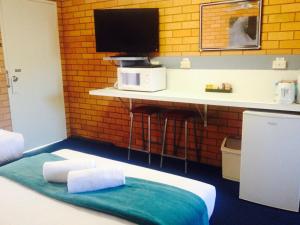 Habitación con cama y escritorio con TV. en Bosuns Inn Motel, en Coffs Harbour