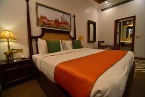 um quarto com uma cama grande e um cobertor laranja em Haveli Dharampura - UNESCO awarded Boutique Heritage Hotel em Nova Deli