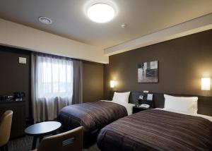 a hotel room with two beds and a table at ​Hotel Route-Inn Ube​ in Ube