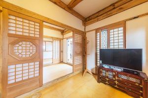 a living room with a flat screen tv and windows at Canopus Resort Pension in Seogwipo