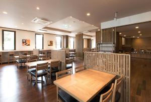 uma sala de jantar com mesas e cadeiras de madeira em Hotel Route-Inn Higashiomi Yokaichi Ekimae em Yōkaichi