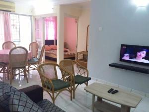 a living room with chairs and a tv on a wall at PD Perdana Homestay Pool side in Port Dickson