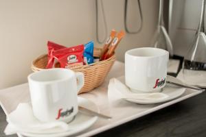 two white cups and a basket of utensils on a tray at H Boutique Peña Parda in La Herradura