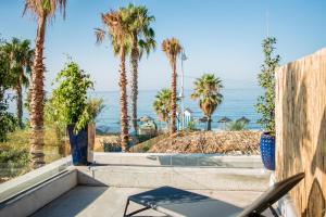 a patio with palm trees and the ocean in the background at H Boutique Peña Parda in La Herradura