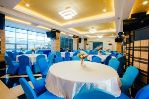 a banquet hall with tables and blue chairs at Facade Hotel in Tabaco