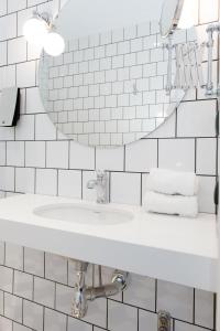 Baño blanco con lavabo y espejo en Clarion Collection Hotel Borgen, en Örebro