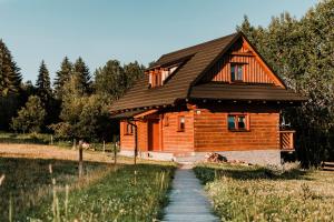 drewniany dom z czarnym dachem i ścieżką w obiekcie Chata nad Briežkami w mieście Rakowa