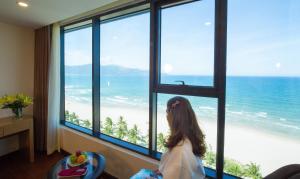ダナンにあるMuong Thanh Luxury Danang Beach Hotelの海の窓から見る少女
