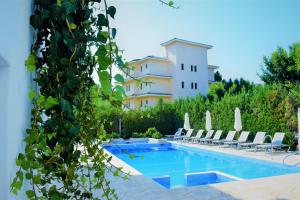 a pool with chairs and a building in the background at Apartamentos Sureda in Canyamel