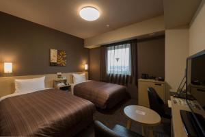 鹿嶋市にあるホテルルートイン鹿嶋のベッド2台とテレビが備わるホテルルームです。