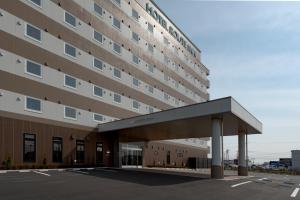 a large building with a parking lot in front of it at Hotel Route-Inn Kashima in Kashima
