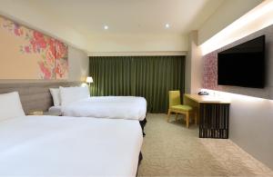 a hotel room with two beds and a television at Aeris International Hotel in Taichung