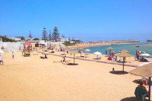 un grupo de personas en una playa con sombrillas en Appart Clim Wifi 700m de la Plage, en Saidia 