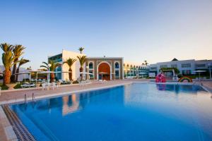 a large swimming pool with chairs and buildings in the background at El Mouradi Cap Mahdia in Mahdia