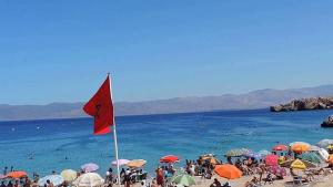 a group of people on a beach with a red flag at Appart Clim Wifi 700m de la Plage in Saïdia