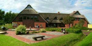 a large building with people sitting on benches in front of it at Ferienhäuser Dornumersiel in Dornumersiel