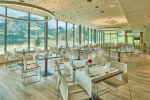 un restaurante con mesas, sillas y ventanas en Hostellerie am Schwarzsee en Bad-Schwarzsee