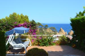 un patio con 2 sillas y una sombrilla y el océano en Blanca Paloma - Holiday House, en Tossa de Mar