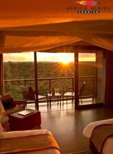 a hotel room with a view of the sun setting at Victoria Falls Safari Club in Victoria Falls