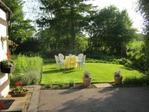 a yellow table and chairs in a garden at THE MOATS - CODDINGTON A small private thatched cottage B&B located in quiet countryside between Ledbury and Malvern - convenient for the Malvern Three Counties Showground and 5 miles from excellent shops restaurants and Ledbury Poetry Festival in Ledbury