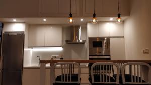 una cocina con armarios blancos y una mesa de madera con sillas. en Luxury Catedral, en Málaga