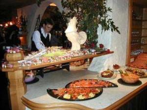 a buffet with food and a man in a room at Hotel Bergland in Lermoos