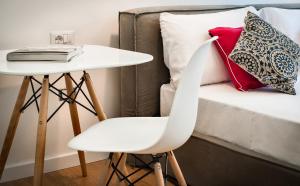a table and a white chair next to a bed at Teku Sardinia Boutique Hotel in Bari Sardo