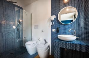 a bathroom with a sink and a toilet and a mirror at Teku Sardinia Boutique Hotel in Bari Sardo