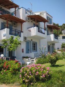 a building with a table and chairs and flowers at Castello Apartments in Stalida