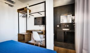 a room with a blue bed and a desk and a sink at Teku Sardinia Boutique Hotel in Bari Sardo