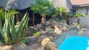 - une piscine bordée de palmiers et de rochers à côté d'une maison dans l'établissement Nkwasi Lodge, à Parys