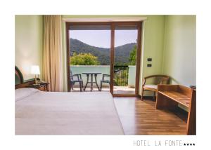 a bedroom with a bed and a balcony with a table at La Fonte Hotel in Ome