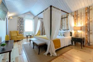 een slaapkamer met een hemelbed en een stoel bij Villa Rio Guest House Suites in Portimão