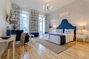 Villa Rio Guest House Suites في بورتيماو: غرفة نوم بسرير ازرق وطاولة وكراسي