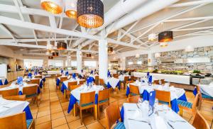 a dining room with white tables and blue chairs at Globales Bouganvilla in Sa Coma