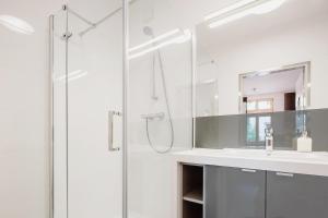uma casa de banho branca com um chuveiro e um lavatório. em Sewa Apartments em Cracóvia