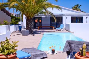 a pool with a palm tree next to a house at Manuki Mas in Vall-Llobrega