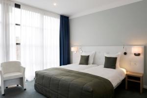 a bedroom with a large bed and a chair at Hotel Boomgaard in Lanaken +53 photos