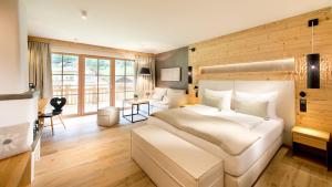 a bedroom with a large white bed and a desk at Living & Spa Vitalhotel Edelweiss in Neustift im Stubaital +56 photos