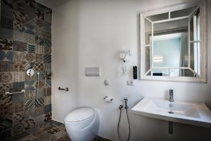 a bathroom with a toilet and a sink and a window at Teku Sardinia Boutique Hotel in Bari Sardo