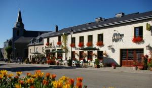 een groot wit gebouw met bloemen ervoor bij Auberge Le Relais in Corbion