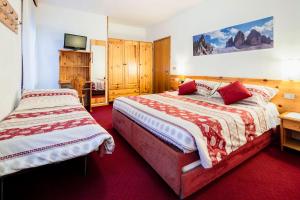 a hotel room with two beds and a tv at Hotel Coldai in Alleghe