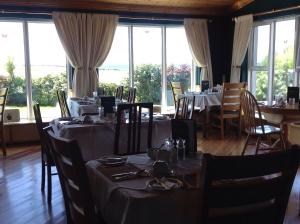a dining room with tables and chairs and windows at Atlantic View House in Doolin +20 photos