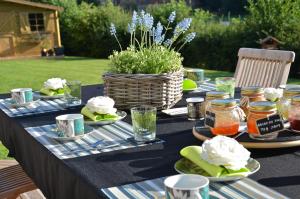 a table with plates of food and a basket of flowers at La Villa Belle in Belle-et-Houllefort