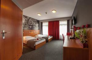 a hotel room with two beds and a desk at Hotel Alexander in Krakow