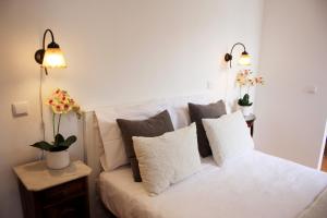 a bedroom with a white bed with pillows and two lights at Molarinho Heritage in Guimarães