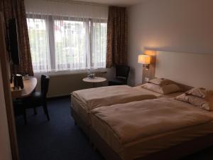 une chambre d'hôtel avec un lit, une table et des chaises dans l'établissement Hotel Kelkheimer Hof, à Kelkheim