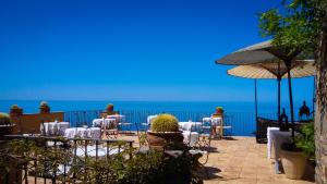 Eine Terrasse mit Tischen und Stühlen, im Hintergrund das Meer. in der Unterkunft Marulivo Hotel in Pisciotta