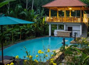 a swimming pool with a gazebo and a house at Khrisna Hs and Cottages in Sidemen